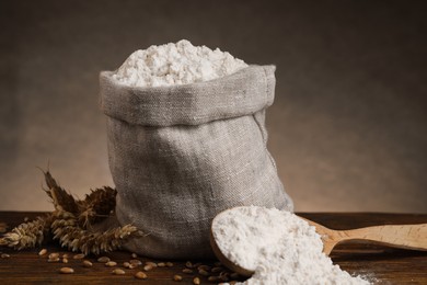 Photo of Wheat flour, grains and spikes on wooden table