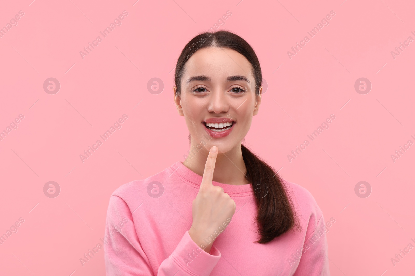 Photo of Beautiful woman showing her clean teeth and smiling on pink background