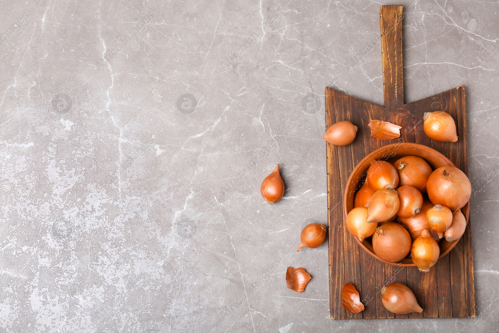 Photo of Bowl with fresh ripe onions on table, top view