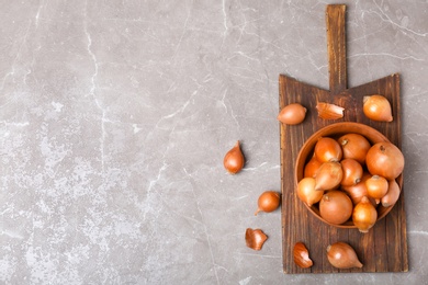 Photo of Bowl with fresh ripe onions on table, top view