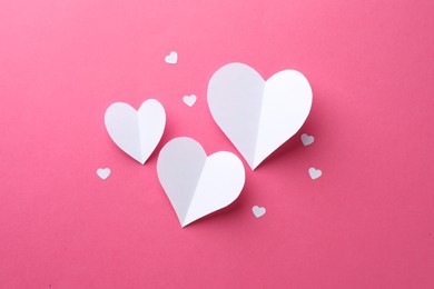 White paper hearts on pink background, flat lay