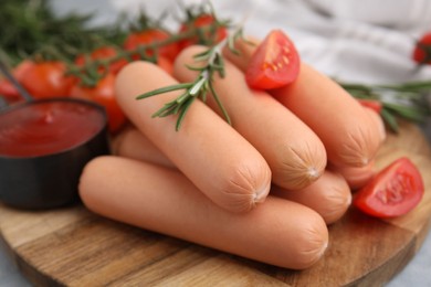 Photo of Delicious boiled sausages, tomatoes and rosemary on gray table, closeup