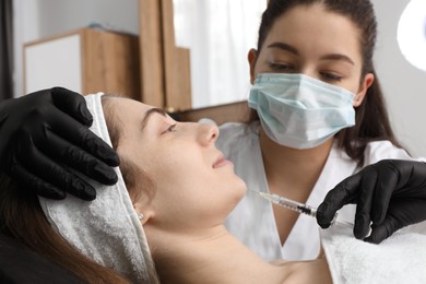 Cosmetologist giving facial injection to patient in clinic, selective focus. Cosmetic surgery