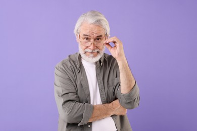 Photo of Portrait of stylish grandpa with glasses on purple background