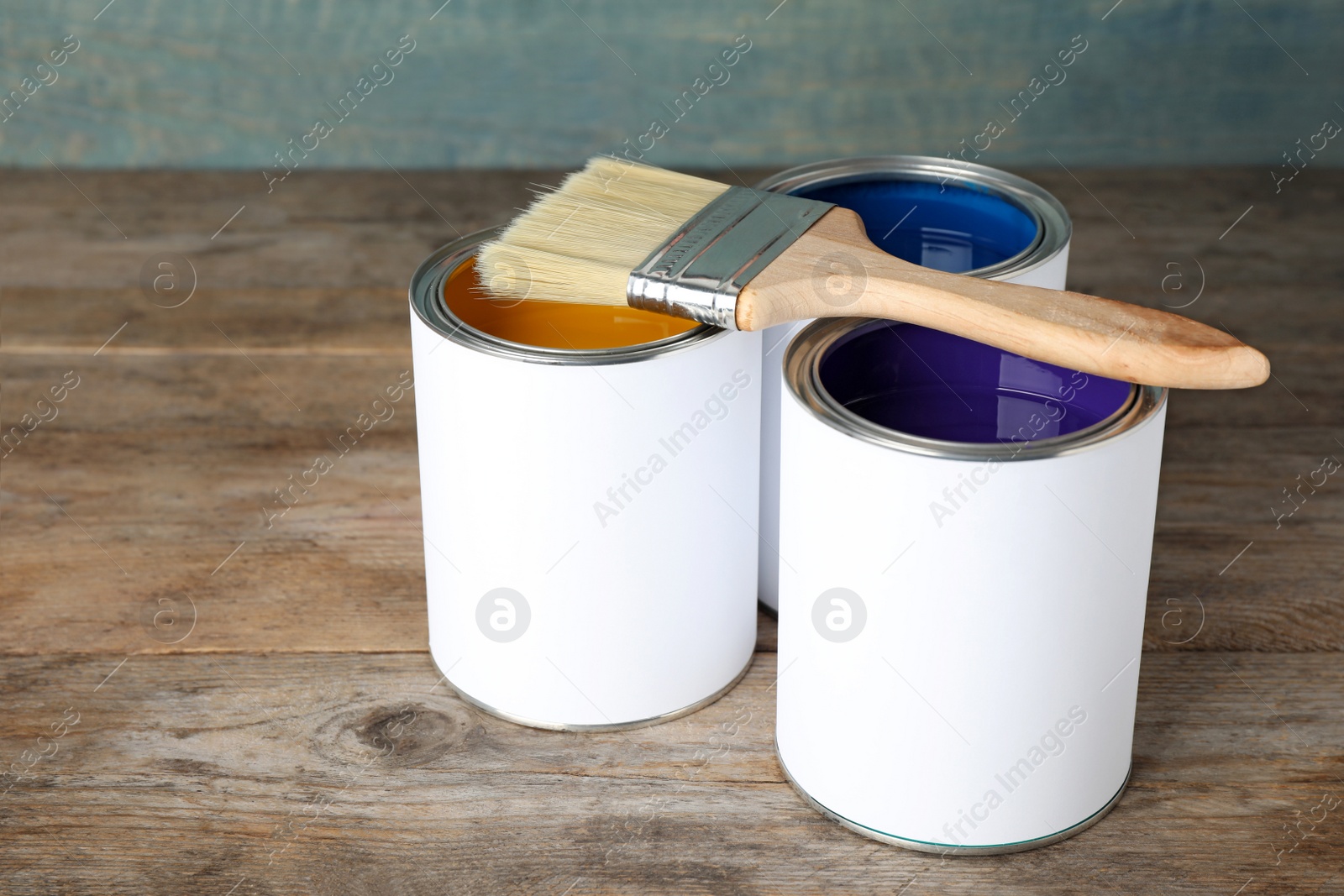 Photo of Cans of paint and brush on wooden table. Space for text