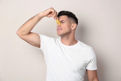 Photo of Man with clothespin on beige background. Runny nose concept
