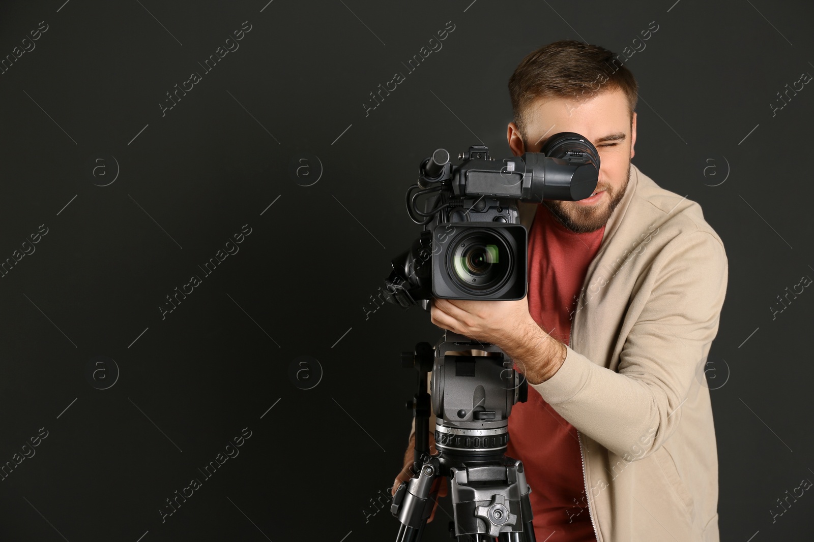 Photo of Operator with professional video camera on black background, space for text