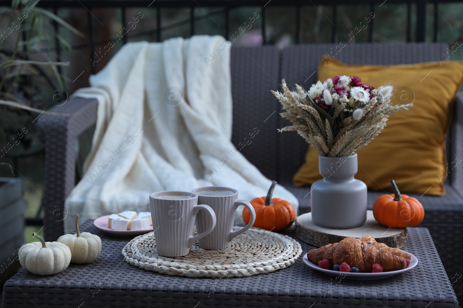 Photo of Rest on terrace with rattan furniture. Drink, dessert and autumn decor on table