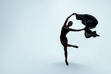 Image of Beautiful ballerina with black veil dancing on light background, space for text. Dark silhouette of dancer