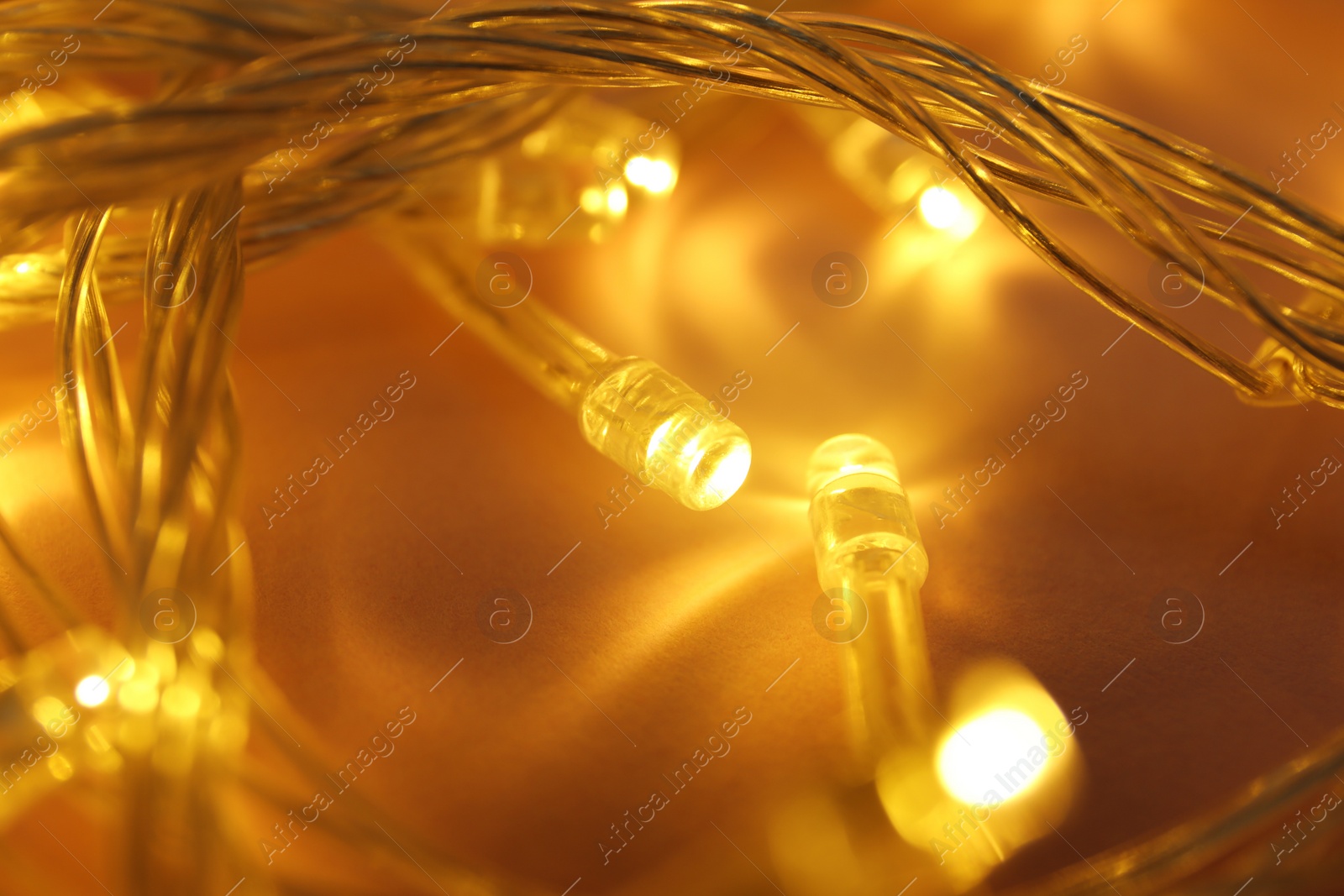 Photo of Glowing Christmas lights on color background, closeup view