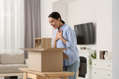 Emotional young woman with opened parcel at home. Internet shopping