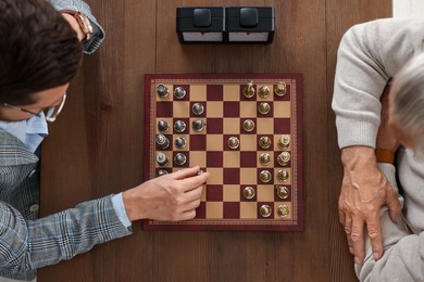 Men playing chess during tournament at wooden table, top view