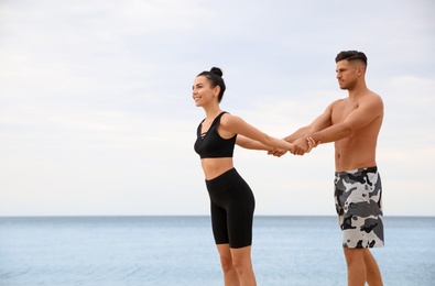 Photo of Couple doing exercise together on beach, space for text. Body training