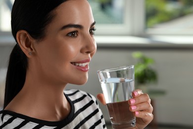 Photo of Young woman with glass of water indoors, closeup. Refreshing drink