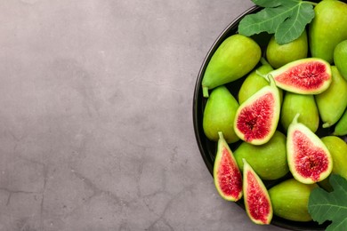 Cut and whole green figs on light gray table, top view. Space for text