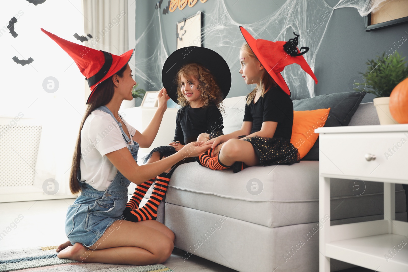 Photo of Mother and cute little girls wearing Halloween costumes at home