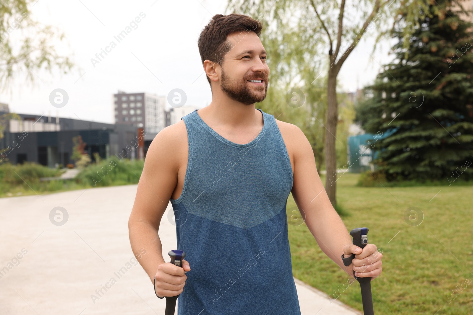 Photo of Man practicing Nordic walking with poles outdoors