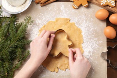 Woman making Christmas cookies with cutters at wooden table, top view