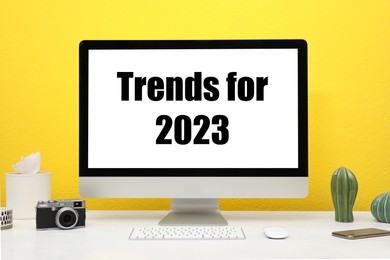 Trends For 2023 text on computer monitor. Workplace with white table