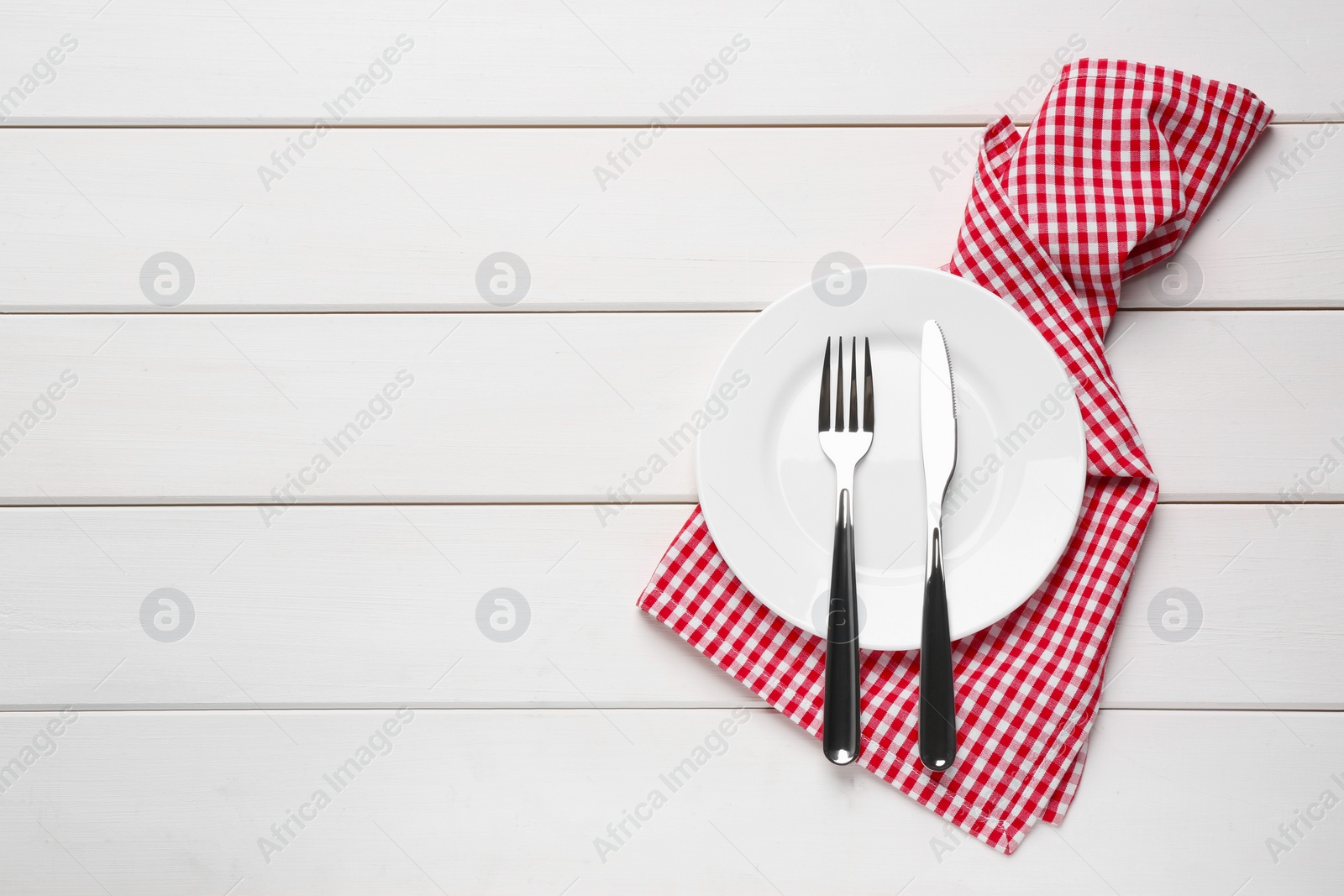 Photo of Ceramic plate, fork and knife on white wooden table, top view