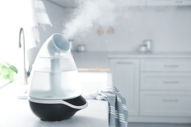 Modern air humidifier on counter in kitchen. Space for text