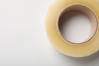 Photo of Roll of adhesive tape on light background, top view. Space for text