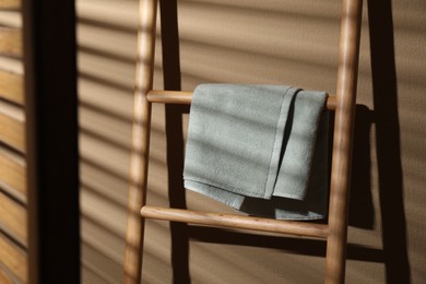 Terry towel on wooden decorative ladder near beige wall