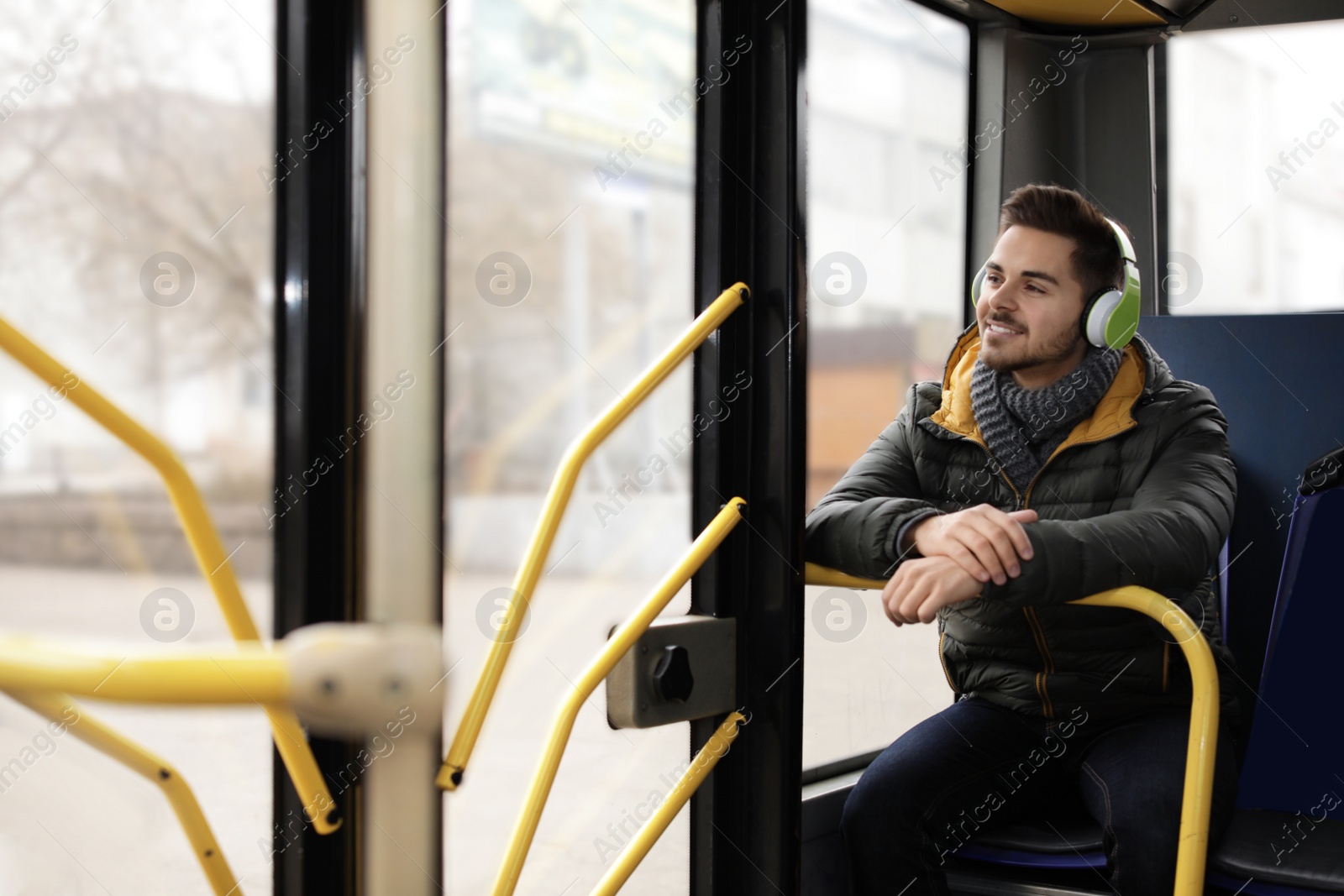 Photo of Young man listening to music with headphones in public transport