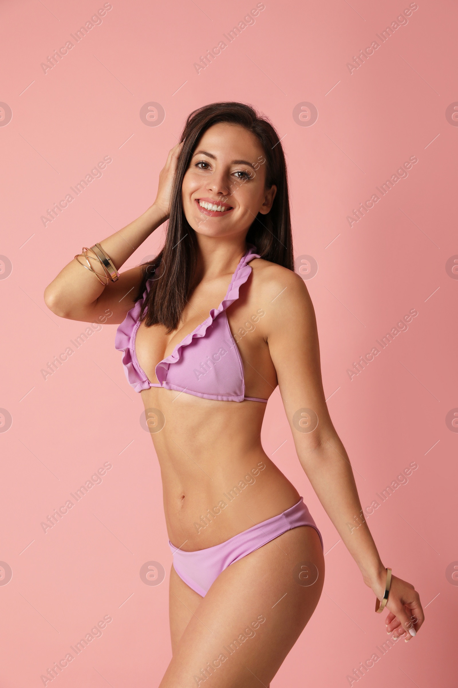 Photo of Pretty sexy woman with slim body in stylish pink bikini on coral background