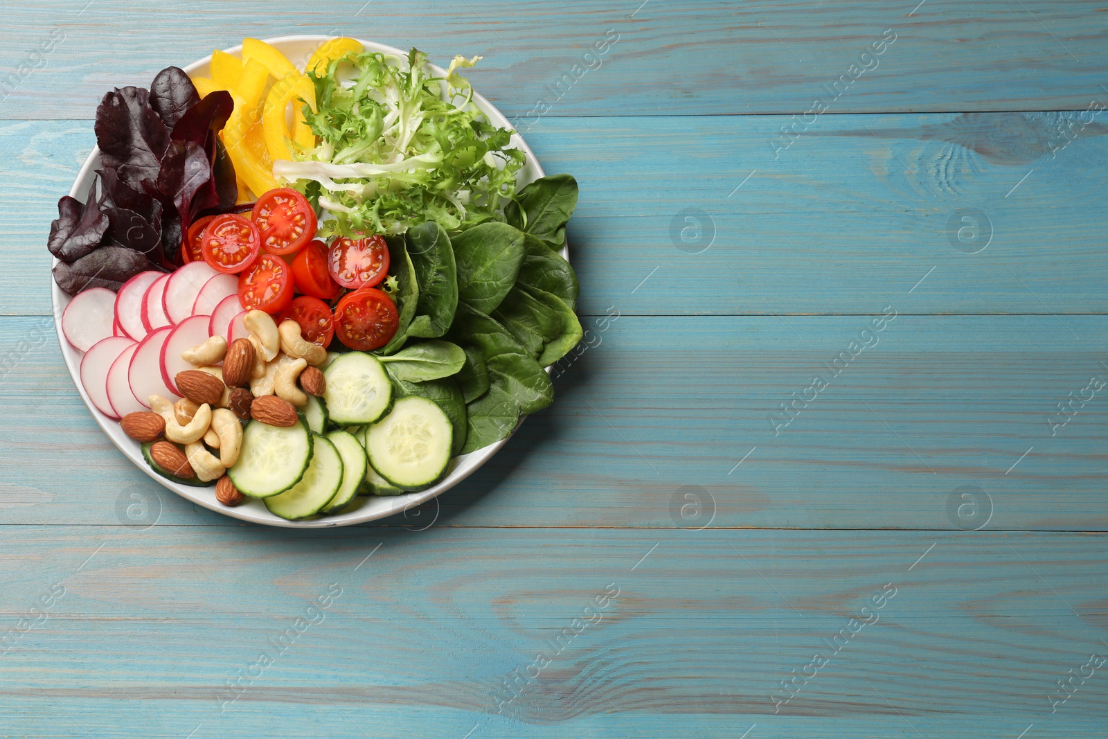 Photo of Balanced diet and vegetarian foods. Plate with different delicious products on light blue wooden table, top view. Space for text