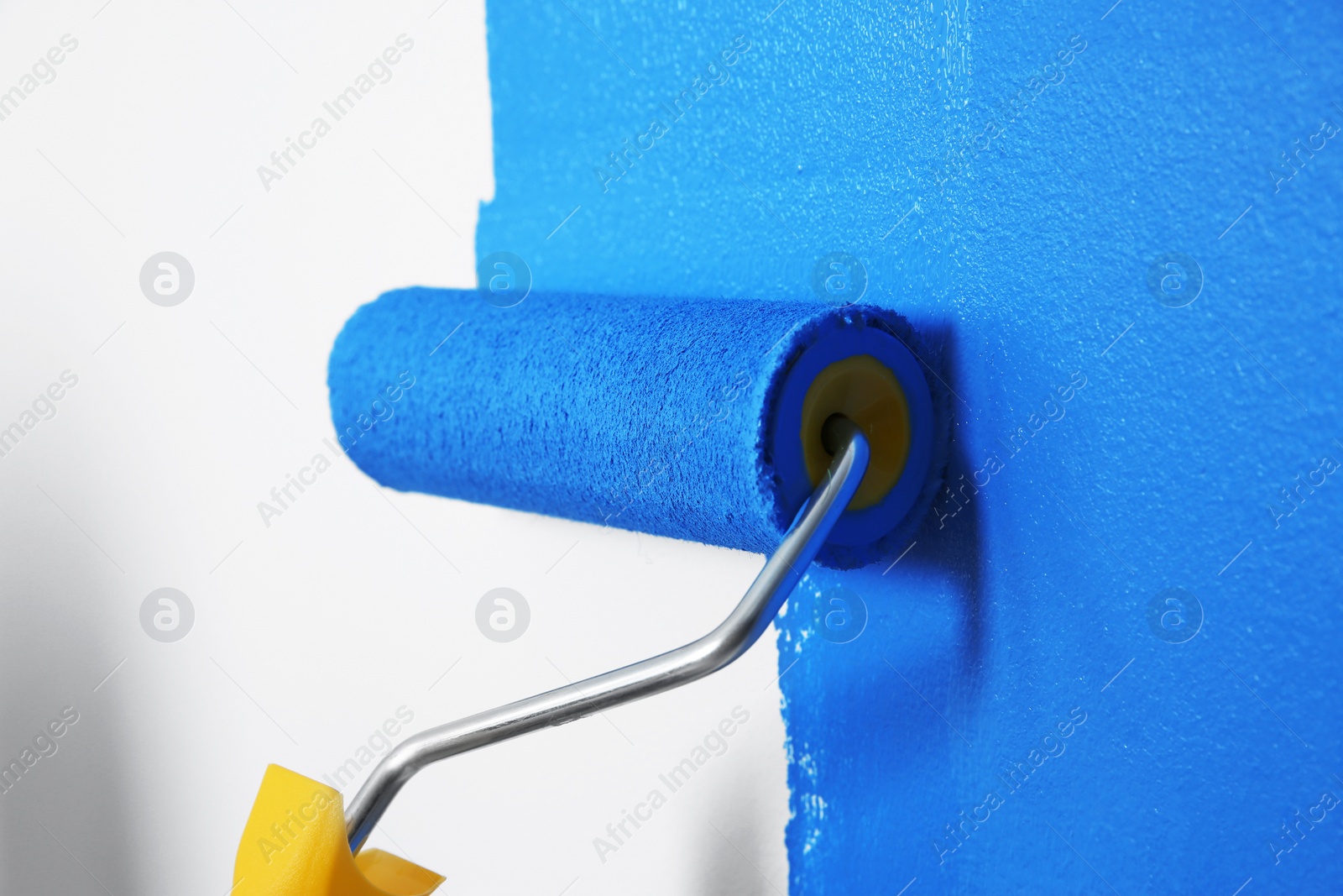 Photo of Painting white wall with blue dye, closeup. Interior renovation