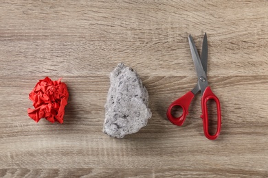 Photo of Flat lay composition with rock, paper and scissors on wooden background