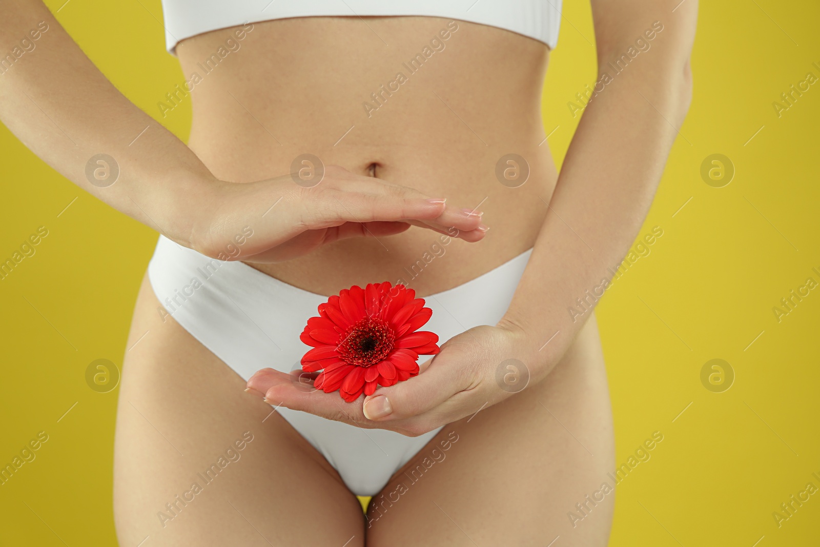 Photo of Gynecology. Woman in underwear with gerbera flower on yellow background, closeup