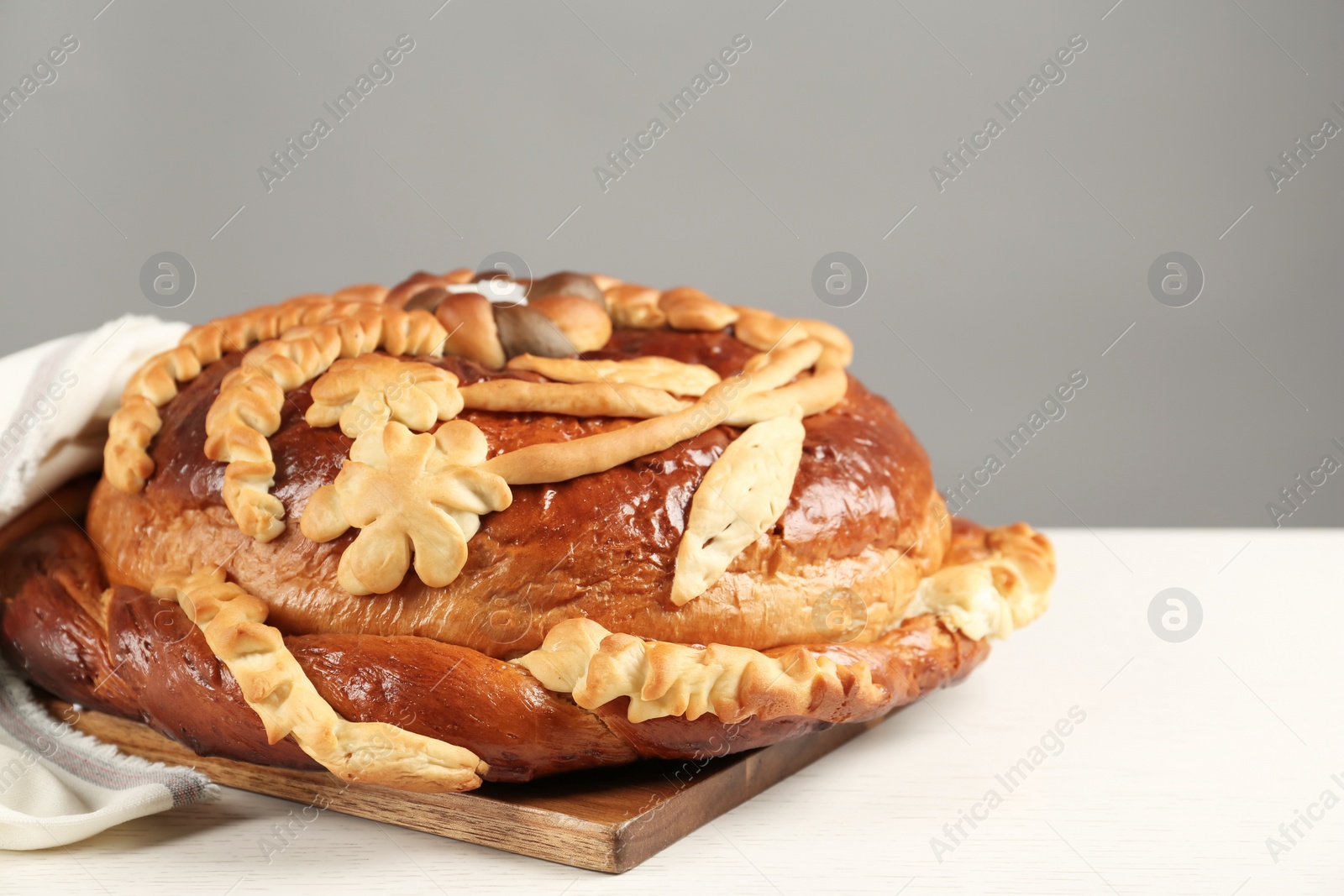 Photo of Korovai on white table against grey background, closeup. Ukrainian bread and salt welcoming tradition