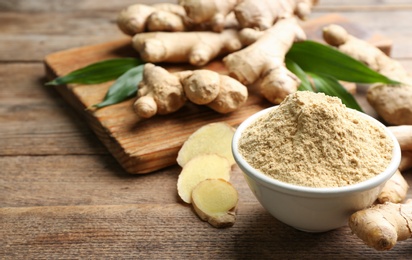 Dry ginger powder, fresh root and leaves on wooden table. Space for text