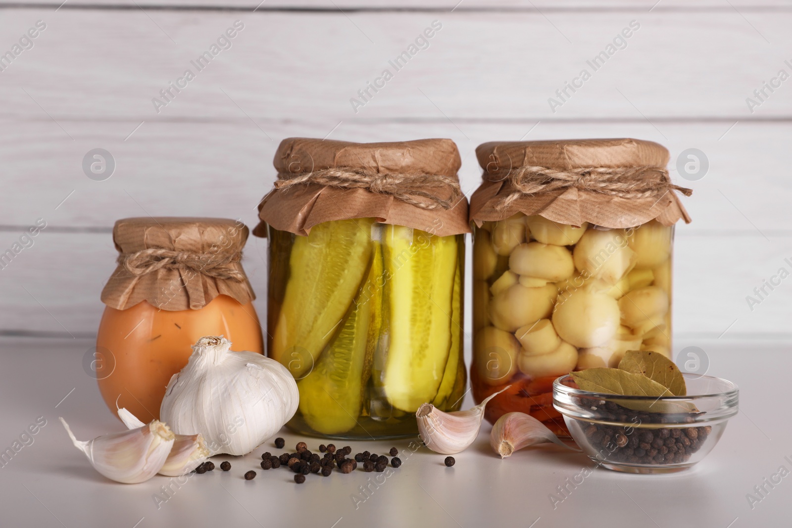 Photo of Jars with different preserved vegetables and fresh spices for canning on light grey table