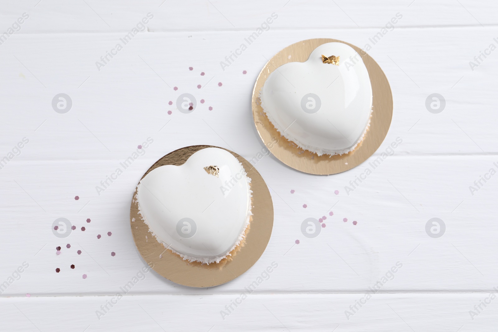 Photo of St. Valentine's Day. Delicious heart shaped cakes and confetti on white wooden table, flat lay