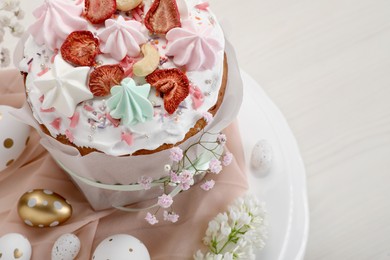 Photo of Traditional Easter cake with meringues and painted eggs on white wooden table, space for text
