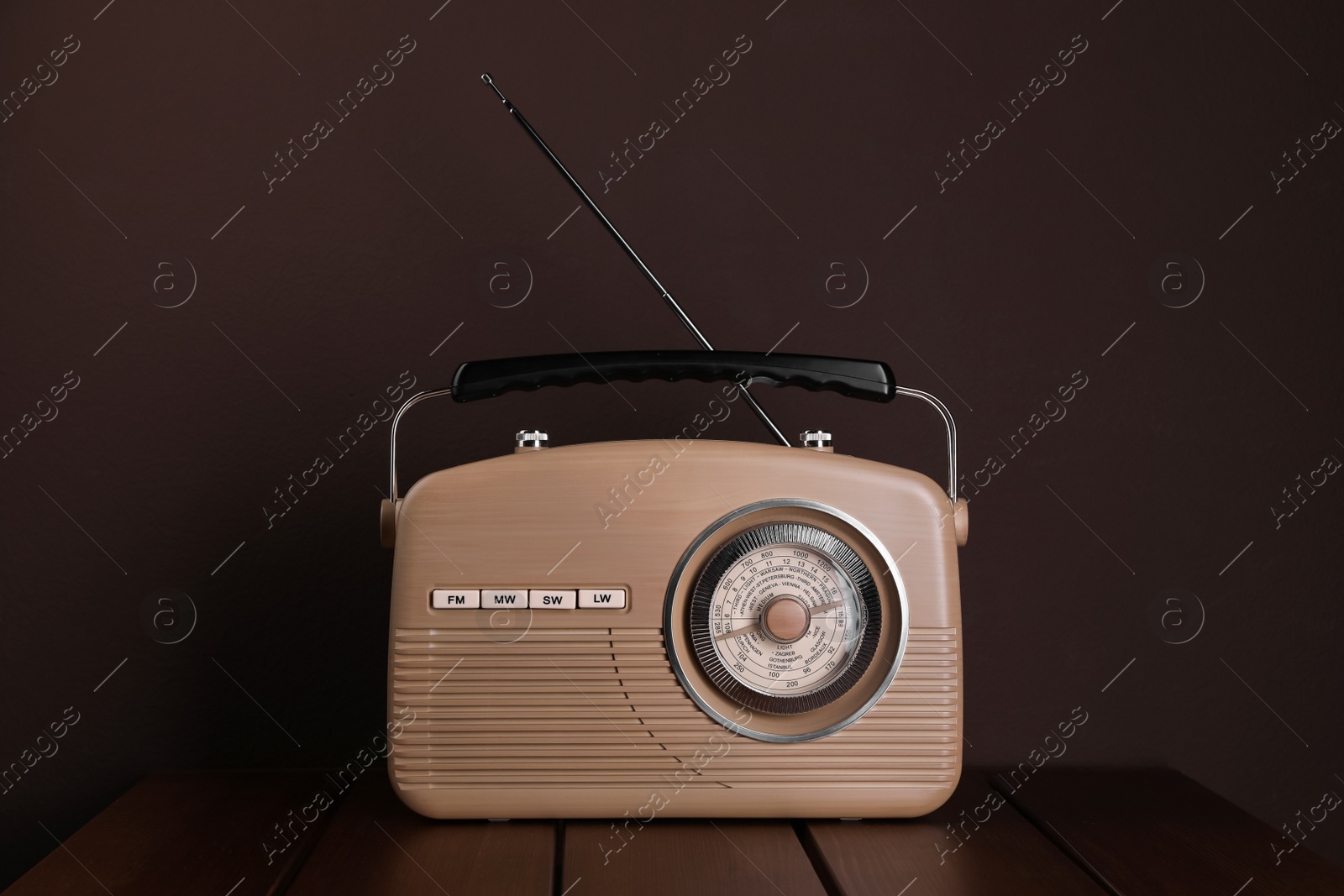 Photo of Retro radio receiver on wooden table against brown background