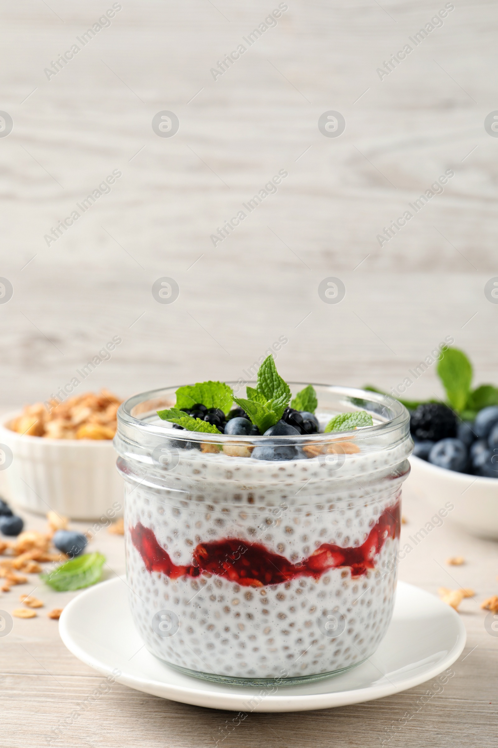 Photo of Delicious chia pudding with berries and granola on wooden table