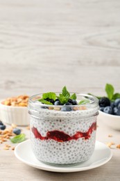 Delicious chia pudding with berries and granola on wooden table