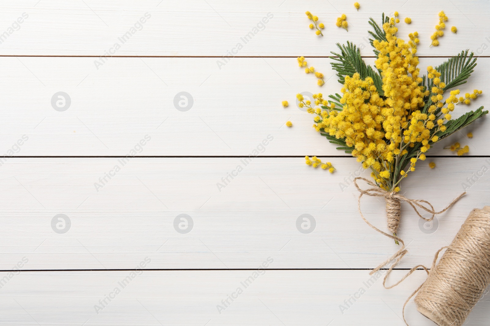 Photo of Beautiful mimosa flowers and twine on white wooden table, flat lay. Space for text