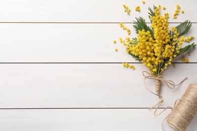 Photo of Beautiful mimosa flowers and twine on white wooden table, flat lay. Space for text