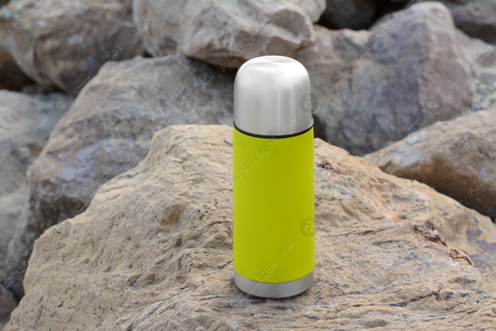 Photo of Metallic thermos with hot drink on stone, space for text