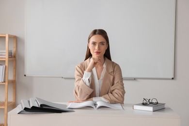 Young teacher sitting at table in classroom