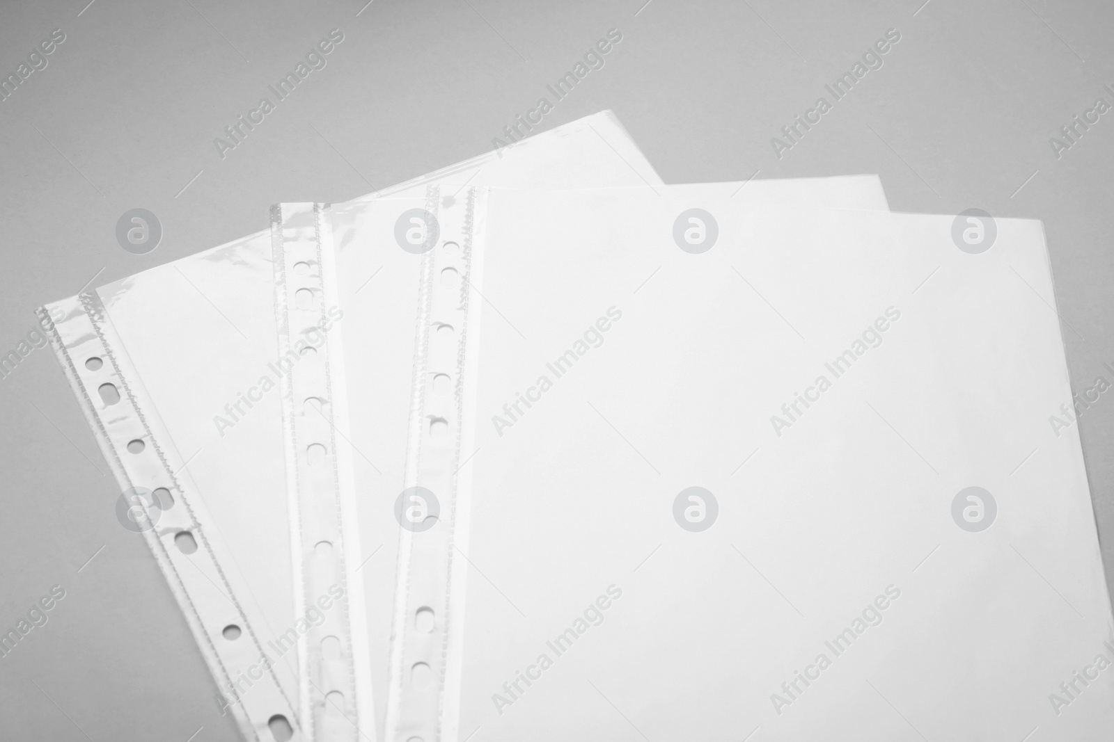 Photo of Punched pockets with paper sheets on light grey background, above view