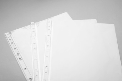 Punched pockets with paper sheets on light grey background, above view