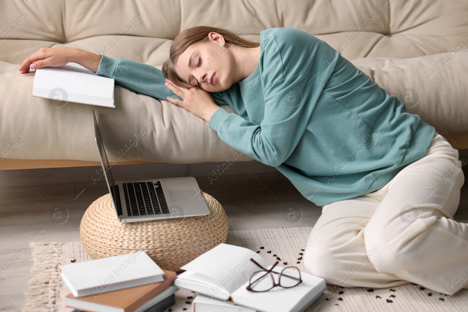 Photo of Young tired woman sleeping near couch at home