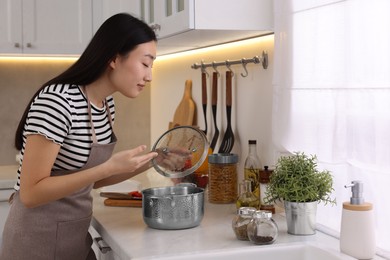 Photo of Beautiful woman smelling soup after cooking in kitchen
