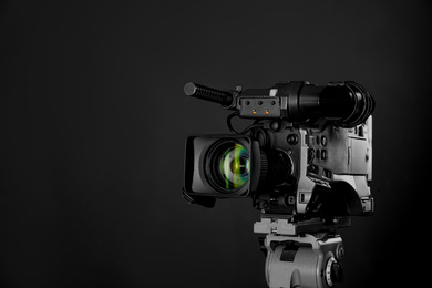 Photo of Modern professional video camera on black background. Space for text